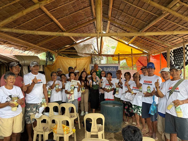 Farmers gathered under a bamboo shelter, each holding a bottle of the treatment.